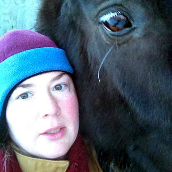 Mountain fleece bomber hat in the snow next to a horse